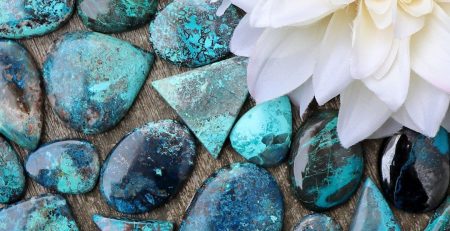 Turquoise stones and a flower on a wooden table.