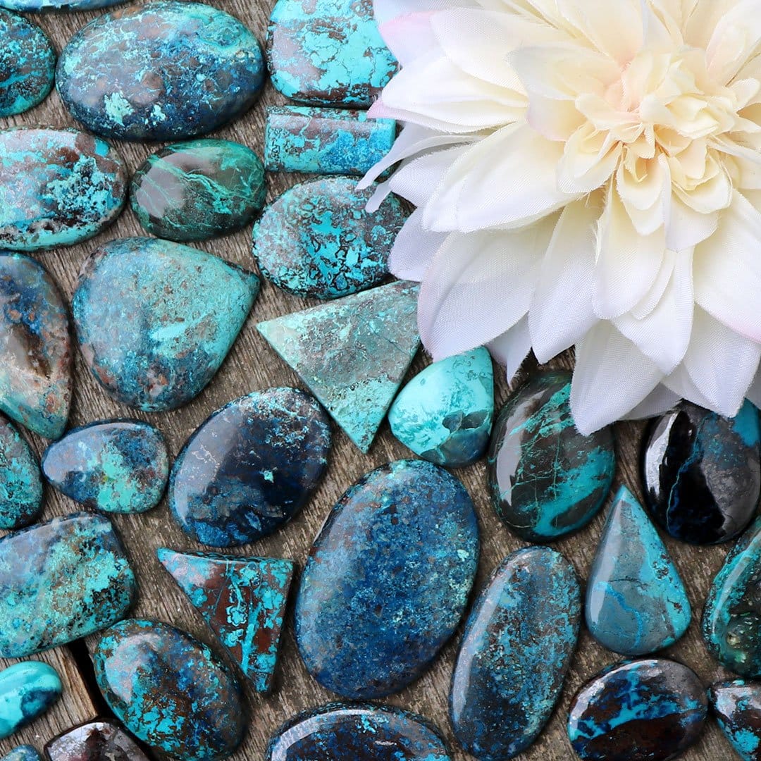 Turquoise stones and a flower on a wooden table.