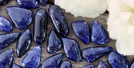 A bunch of blue sapphire stones on a wooden table.