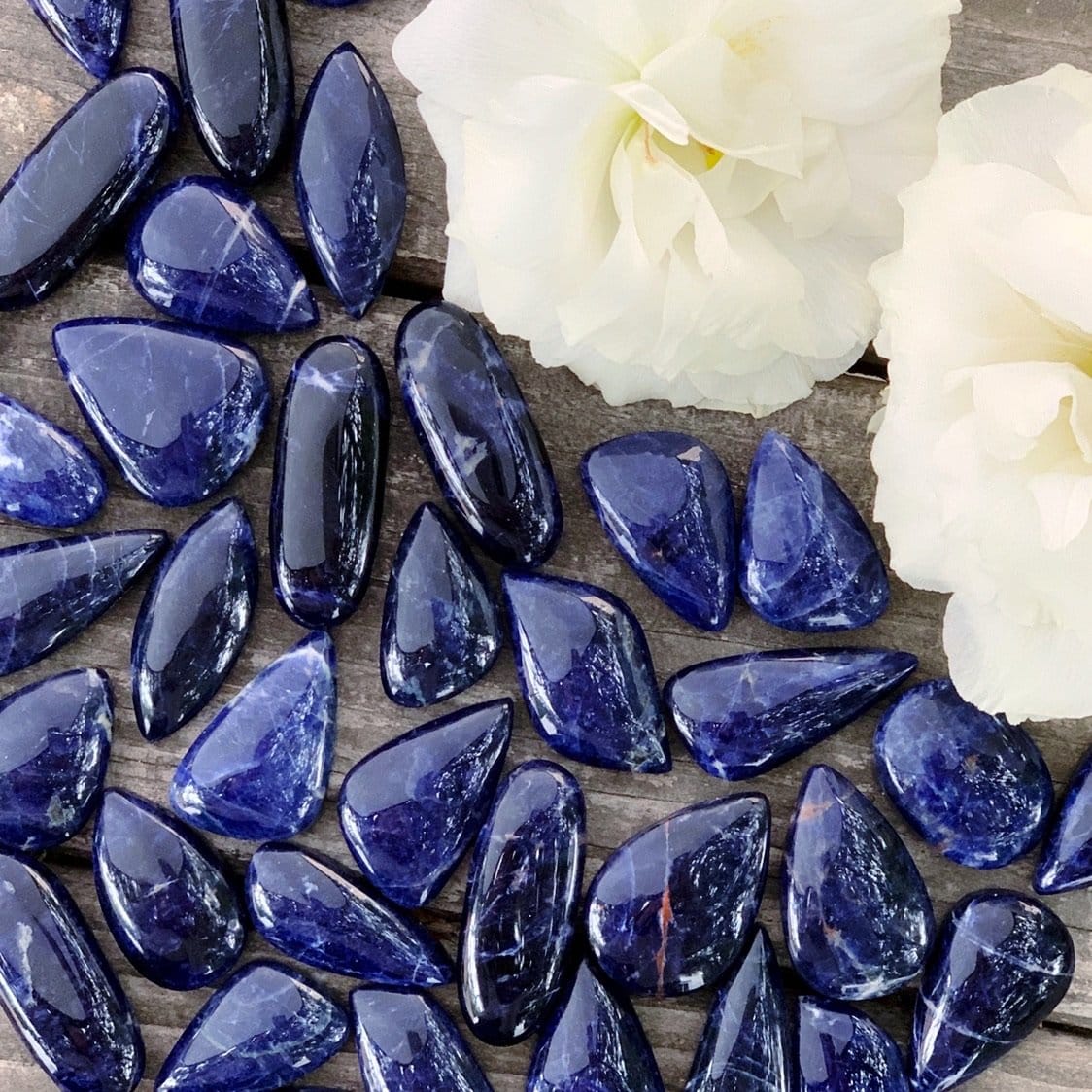 A bunch of blue sapphire stones on a wooden table.