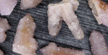 A bunch of pink crystals on a wooden surface.