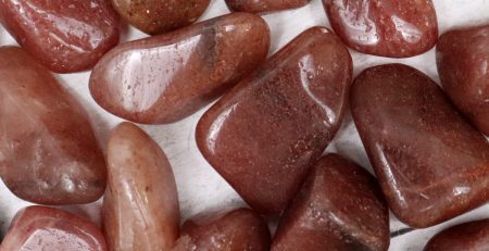 A pile of red jasper stones on a white surface.