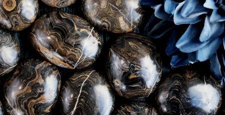 A group of black and blue marble eggs on a wooden table.