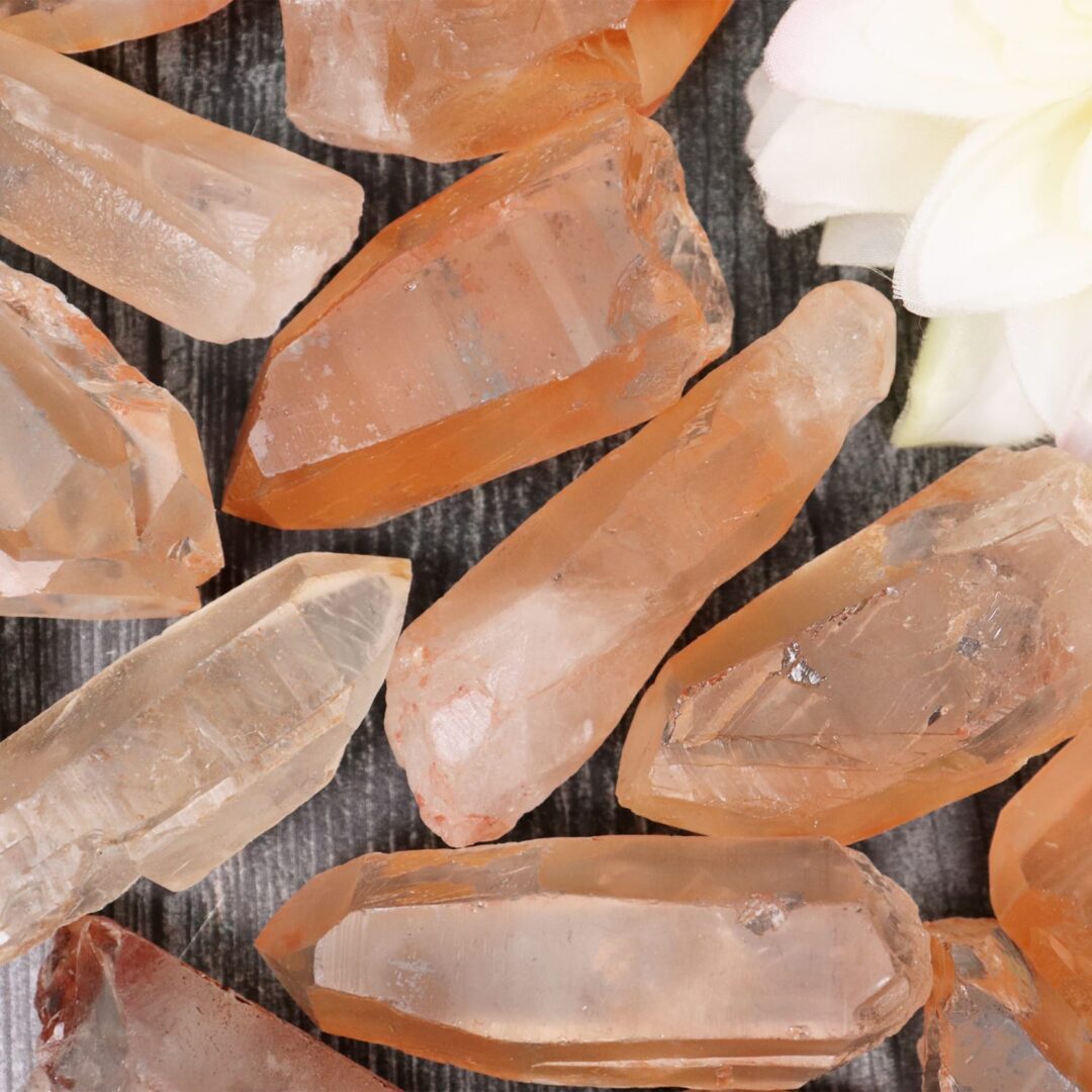 A bunch of orange quartz crystals on a wooden surface.