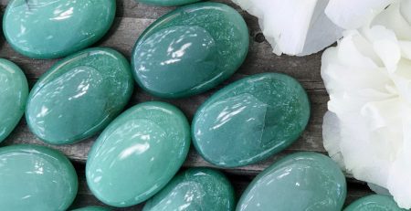 A bunch of green jade stones on a wooden table.