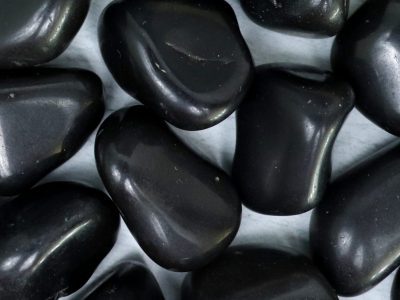 A pile of black pebbles on a white surface.