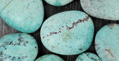 A group of turquoise stones on a wooden table.