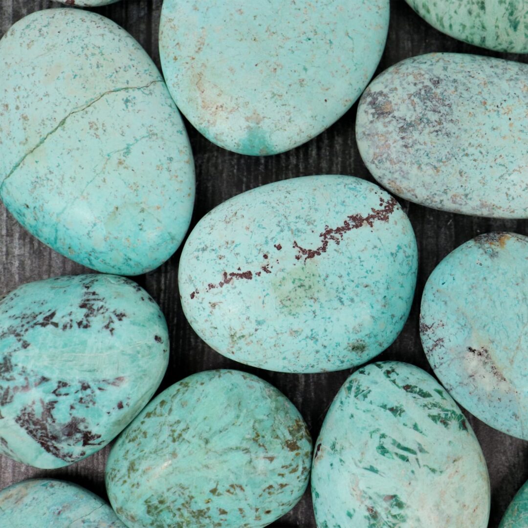 A group of turquoise stones on a wooden table.