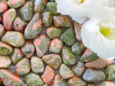 A white flower is placed on a bed of green and pink rocks.