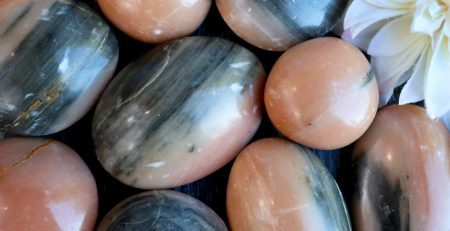 A bunch of peach and black stones with a flower in the middle.