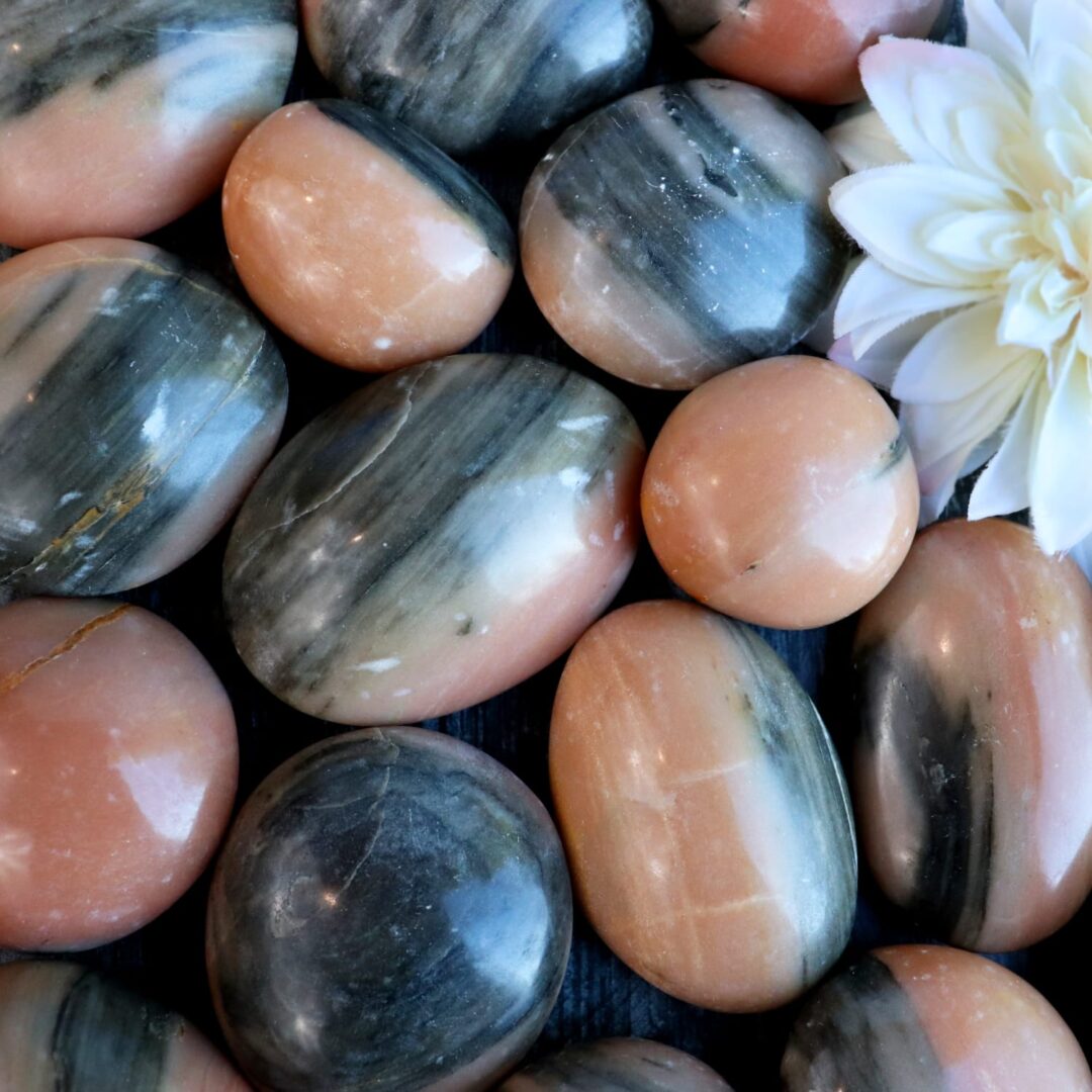 A bunch of peach and black stones with a flower in the middle.