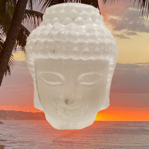 White Buddha statue against sunset sky.