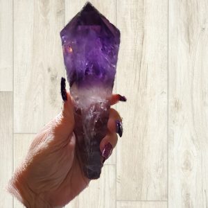 Hand holding a large purple amethyst crystal.