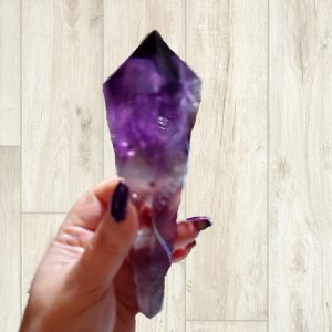 Hand holding a large amethyst crystal.