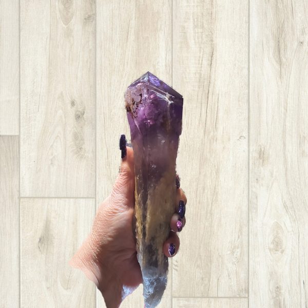 Hand holding a large amethyst crystal.