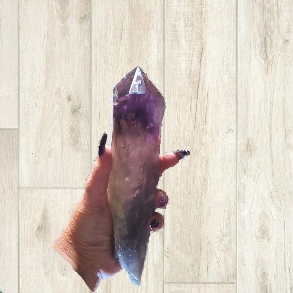 Large amethyst crystal held in hand.