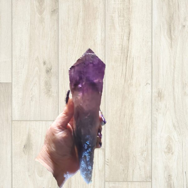 A hand holding a large amethyst crystal.