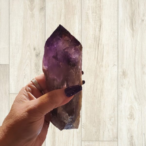 Hand holding large purple amethyst crystal.