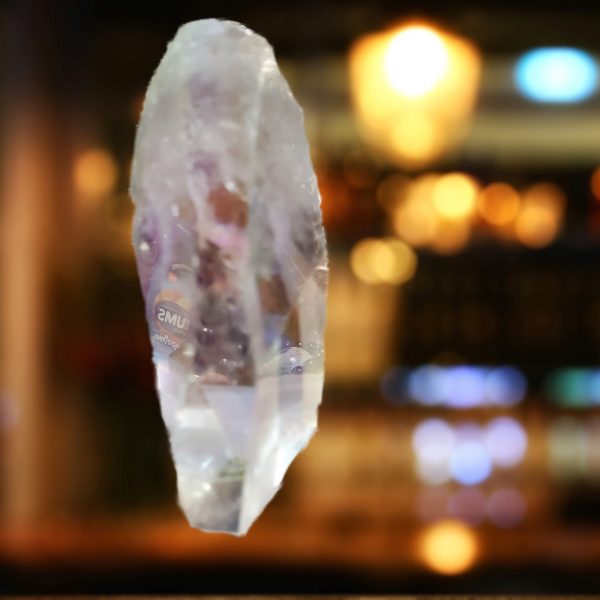 Clear quartz crystal hanging against bokeh.