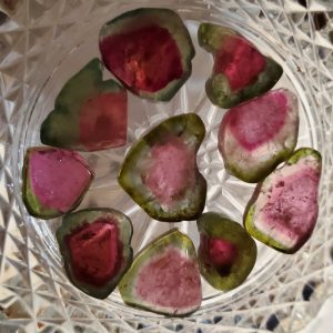 Pink and green tourmaline gemstones in a bowl.