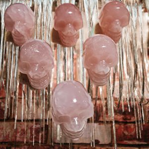 Five pink crystal skull pendants hanging.