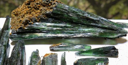 A group of green tourmaline crystals on a table.