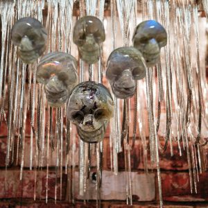 Crystal skull pendants hanging from chains.