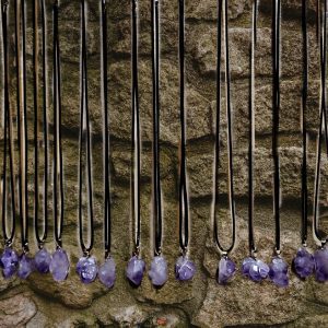 Amethyst necklaces on a stone wall.