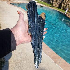 Hand holding a large blue kyanite crystal.