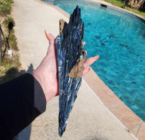Hand holding a large blue kyanite crystal.