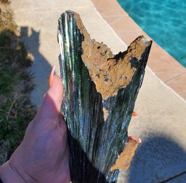Green and brown crystal in hand.