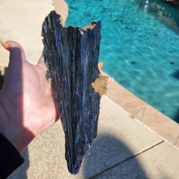 Black and blue crystal in hand by pool.
