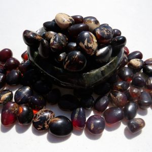 Amber stones in a bowl on a white surface.