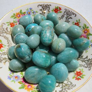 Turquoise gemstone tumbled stones on plate.