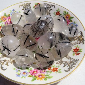 Black tourmaline tumbled stones on a plate.