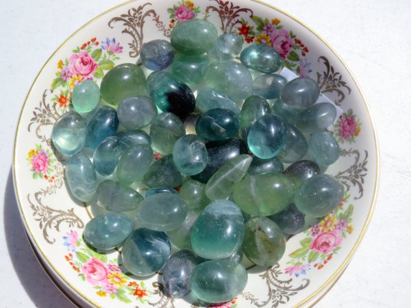 Green stones on floral patterned plate.