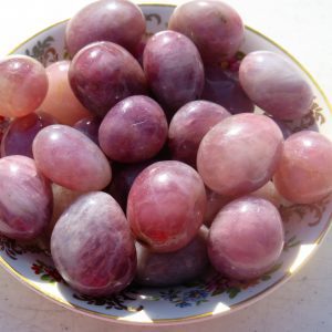 Pink and purple tumbled stones in bowl.