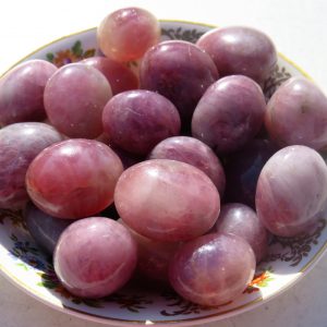 Pink tumbled gemstones on a plate.