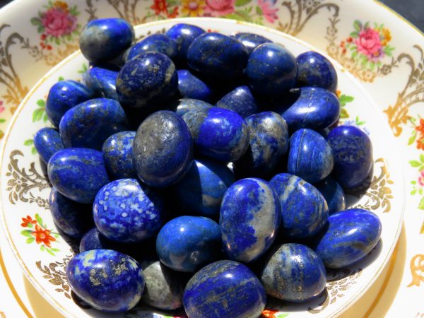 Blue lapis lazuli tumbled stones in a bowl.