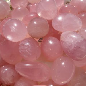 Pink quartz tumbled stones in a bowl.