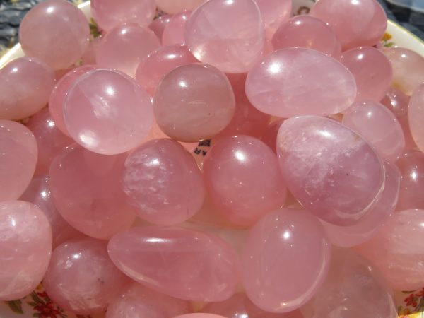 Pink quartz tumbled stones in a bowl.