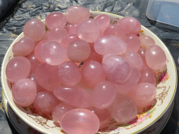 Pink rose quartz tumbled stones in a bowl.