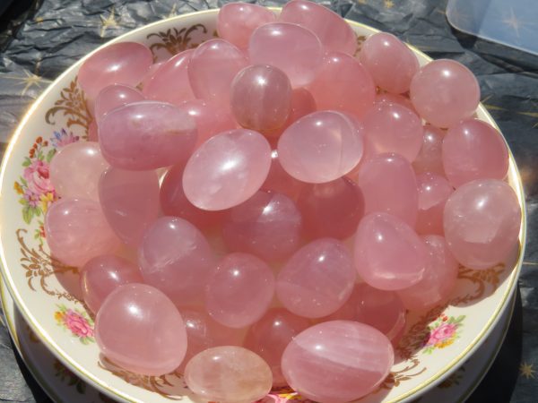 Pink rose quartz tumbled stones in a bowl.
