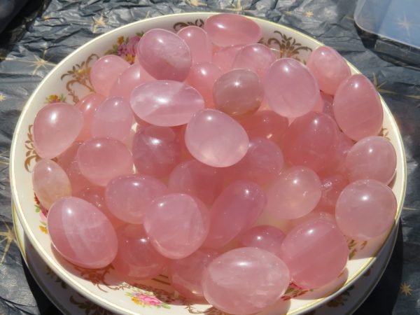 Pink rose quartz tumbled stones in a bowl.