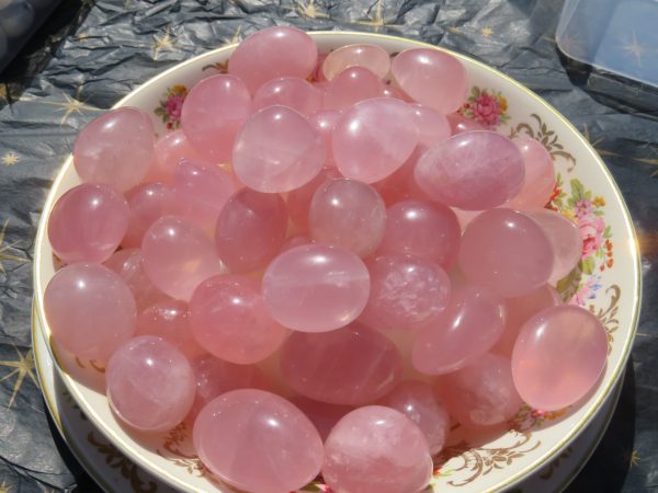 Pink rose quartz tumbled stones on a plate.