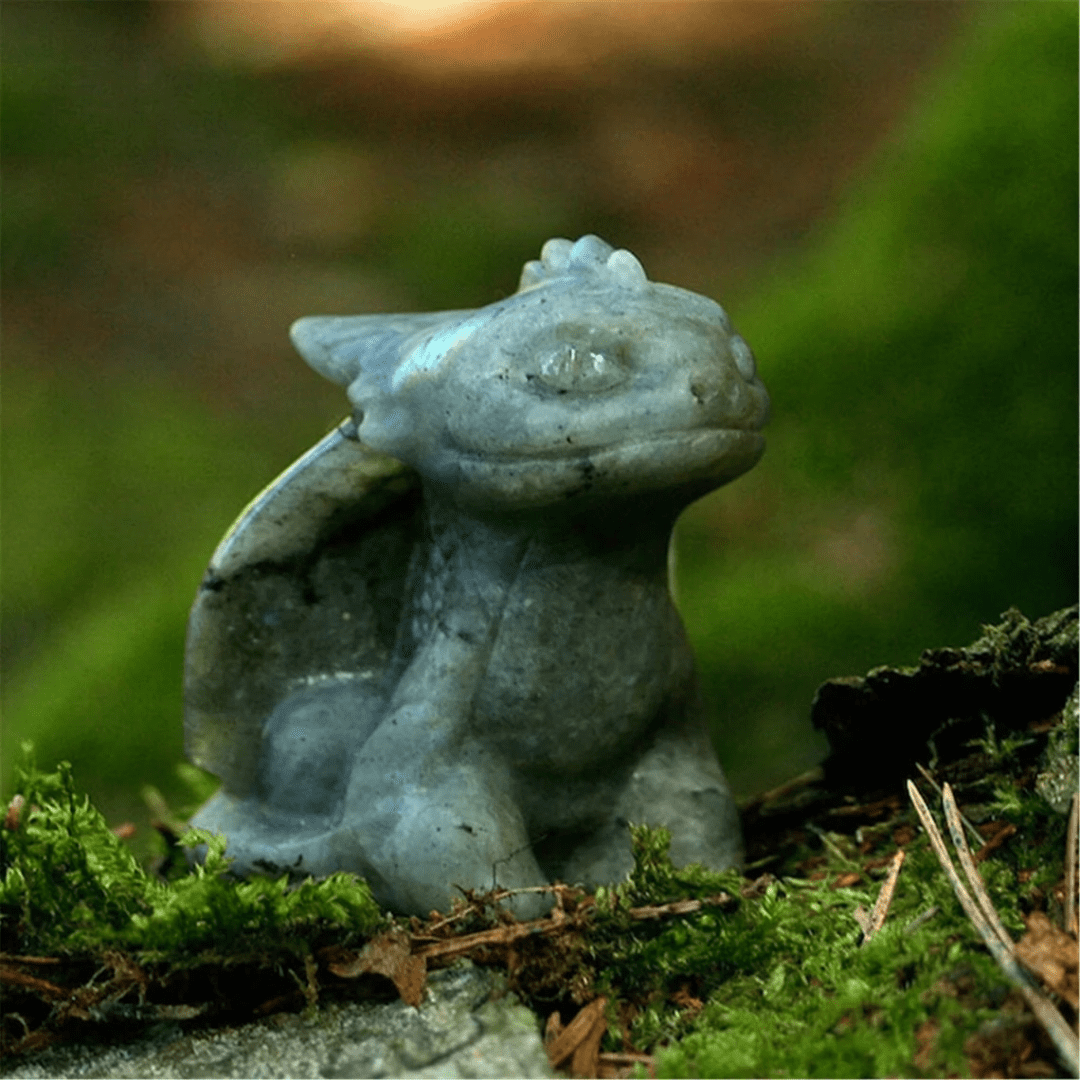 A small statue of a dragon sitting on moss.