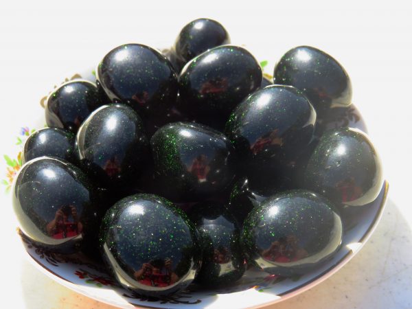 Bowl of shiny green and black eggs.