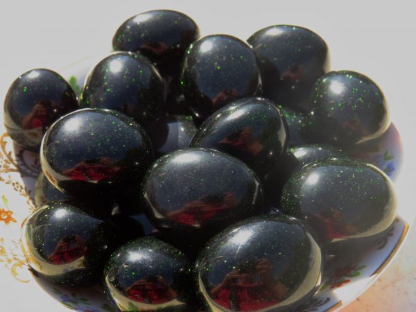 Black and green gemstone spheres in a bowl.