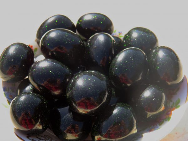 Black and green speckled marbles in a bowl.