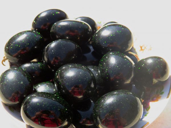 Black and green gemstone eggs in a bowl.
